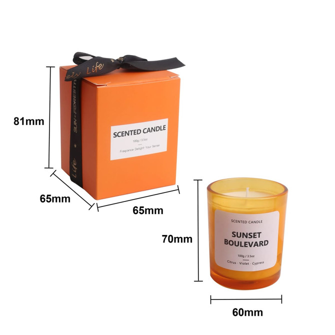 A 3.5oz orange glass candle with a white label and a black ribbon on a matching box.