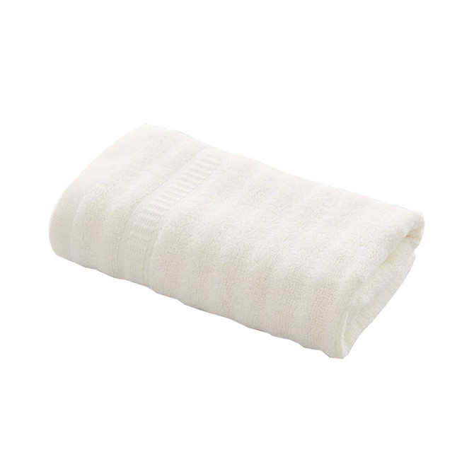 A cream-coloured bamboo fiber towel neatly folded, featuring a textured pattern. It includes a branded tag. A cream-coloured bamboo fiber towel neatly folded, featuring a textured pattern. It includes a branded tag.
