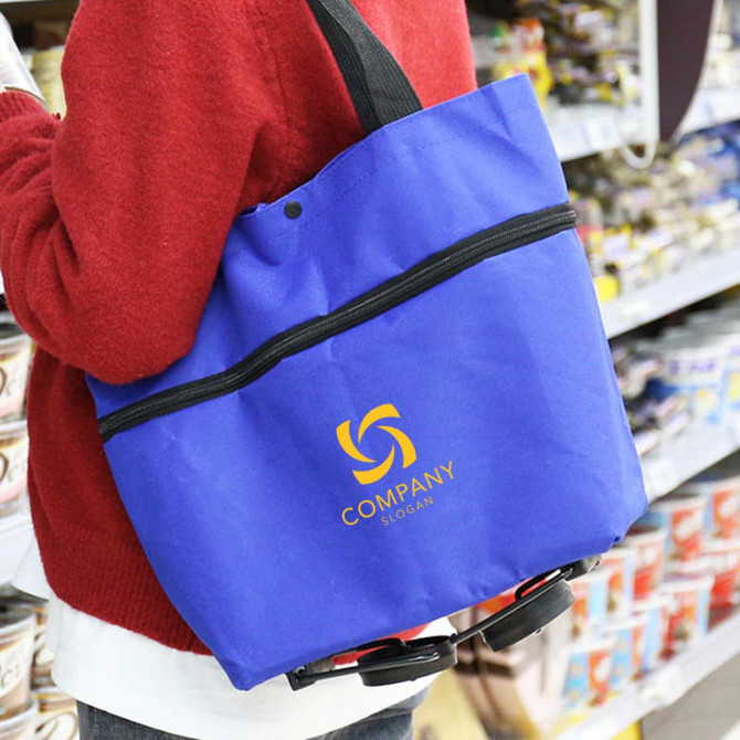 A blue collapsible shopping trolley bag with a logo, being carried in a store. A blue collapsible shopping trolley bag with a logo, being carried in a store.