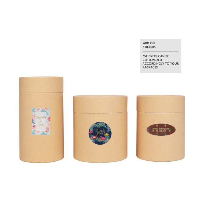 Three small cylindrical paper boxes in kraft brown, featuring various decorative stickers on their surfaces.