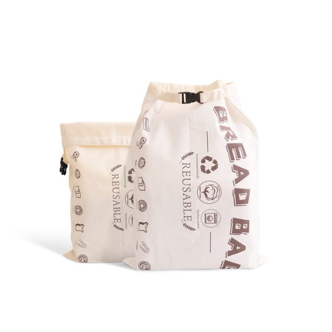 Two cream-coloured linen bread bags with drawstring closures, featuring various printed icons and a logo. Two cream-coloured linen bread bags with drawstring closures, featuring various printed icons and a logo.