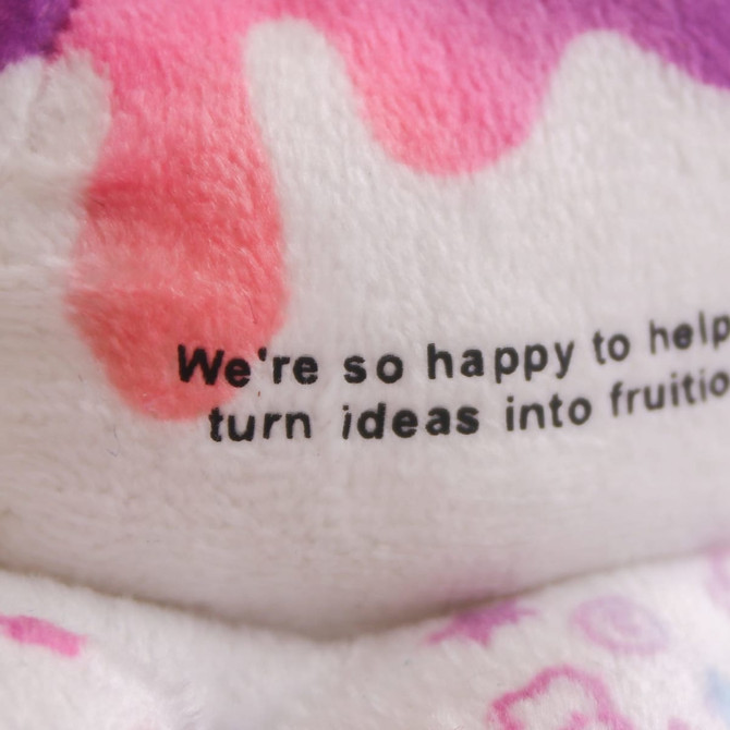 A small, reversible octopus plush toy featuring pink and purple colours. It has a logo on it.