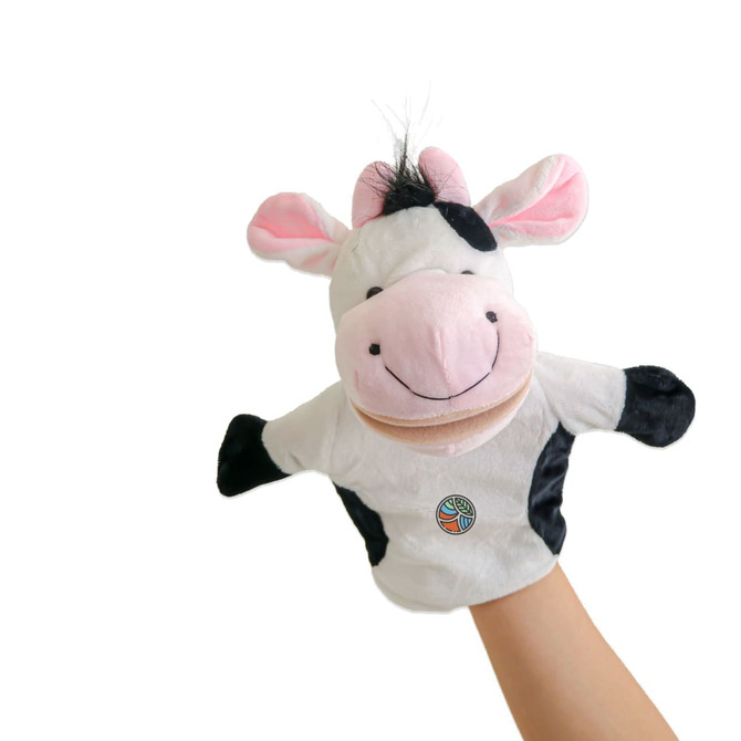 A white and black cow hand puppet with pink ears and a smiling face, held in a hand.