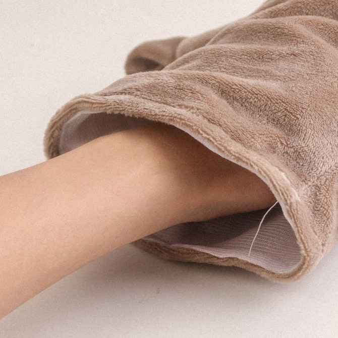 A plush rhinoceros hand puppet in soft beige, featuring a hand inside the puppet's opening.