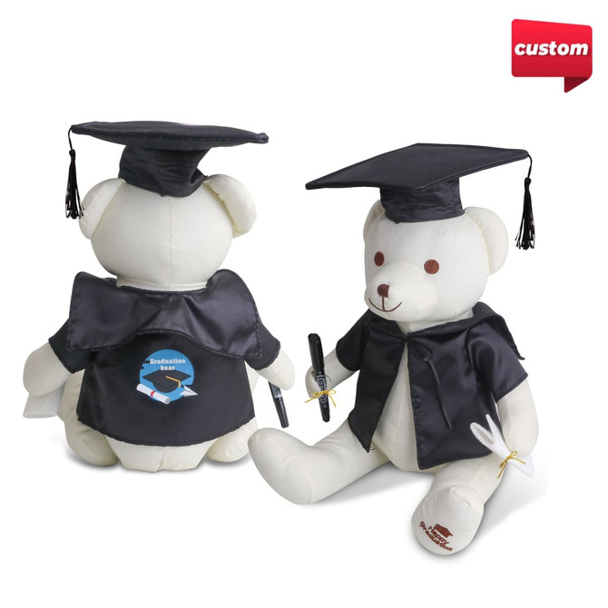 A plush white bear wearing a black graduation cap and gown, holding a pen and featuring a logo.