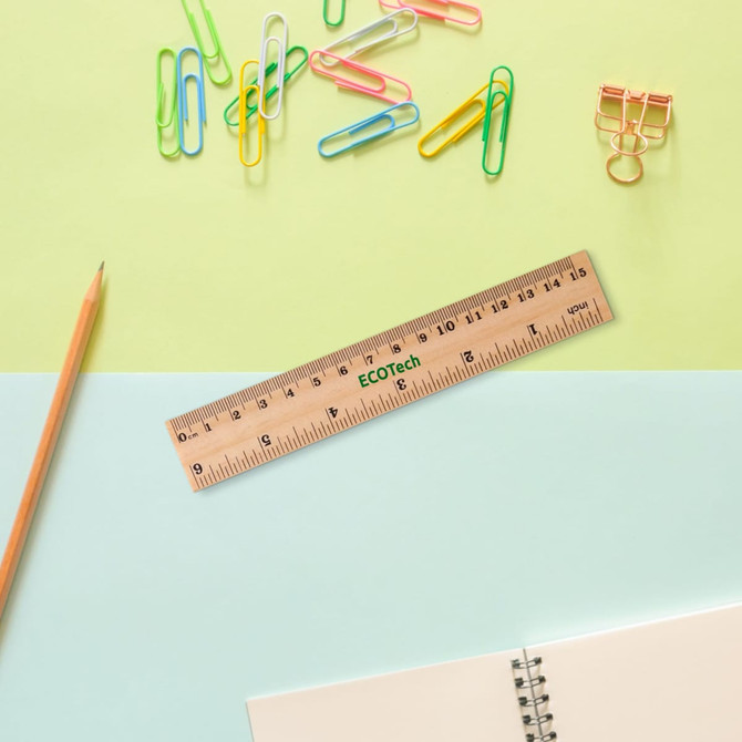 A wooden dual scale ruler rests on a blue and green background, surrounded by colourful paper clips and stationery items.