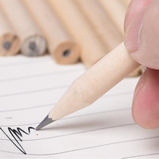 A short grey-lead pencil without an eraser, being used to write on lined paper, with multiple pencils in the background.