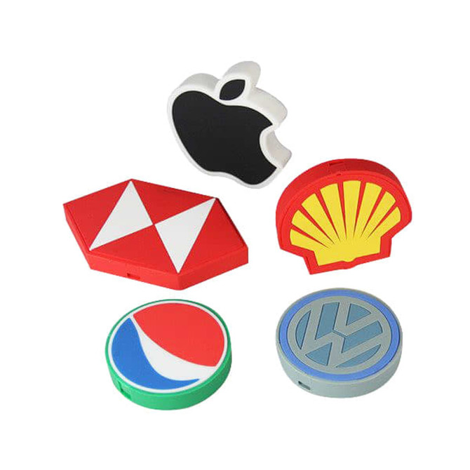 A collection of custom shaped PVC wireless chargers in various colours, featuring different logos and designs.