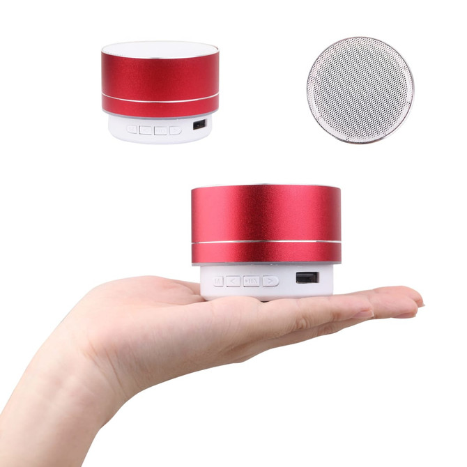 A red metal Bluetooth speaker held in a hand, featuring buttons and a logo on the base.