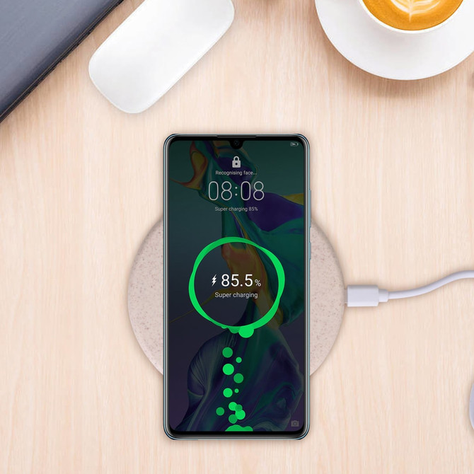 A wireless charger featuring a wheat straw design, paired with a smartphone displaying a charging status, on a wooden surface. A wireless charger featuring a wheat straw design, paired with a smartphone displaying a charging status, on a wooden surface.
