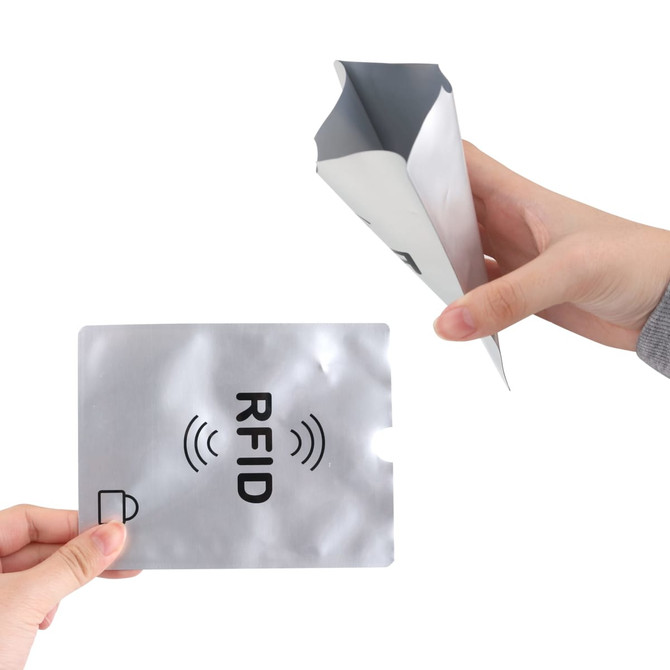 A silver RFID passport holder being held, with a hand displaying a matching RFID card.
