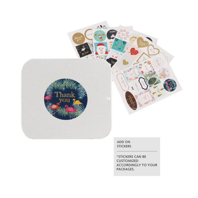 A white slide tin box with a circular design and a collection of colourful stickers displayed beside it.