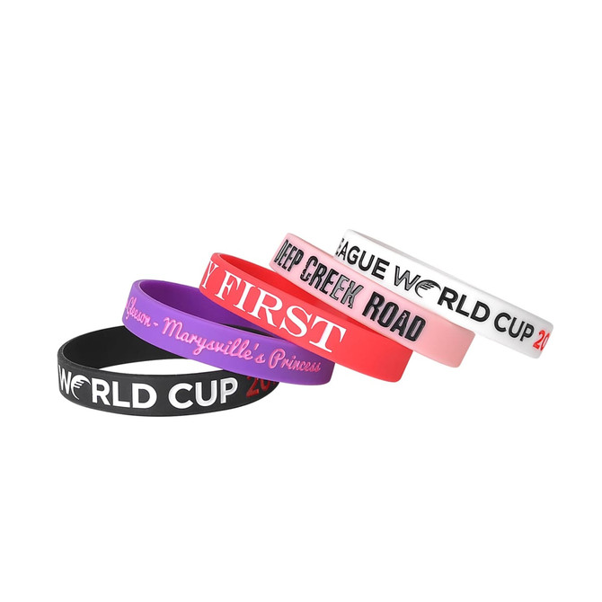 Four debossed silicone wristbands in black, pink, purple, and white, featuring various designs and a logo.