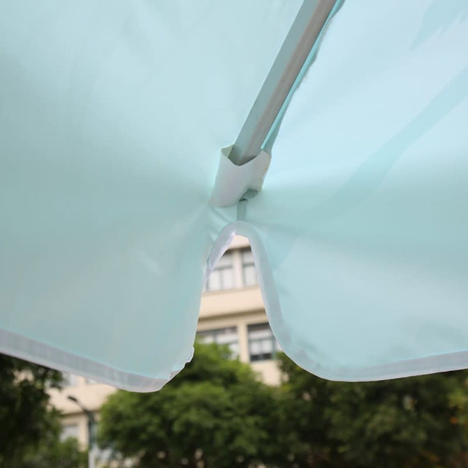 A mint green patio umbrella featuring valances, showing the underside and metal support structure.