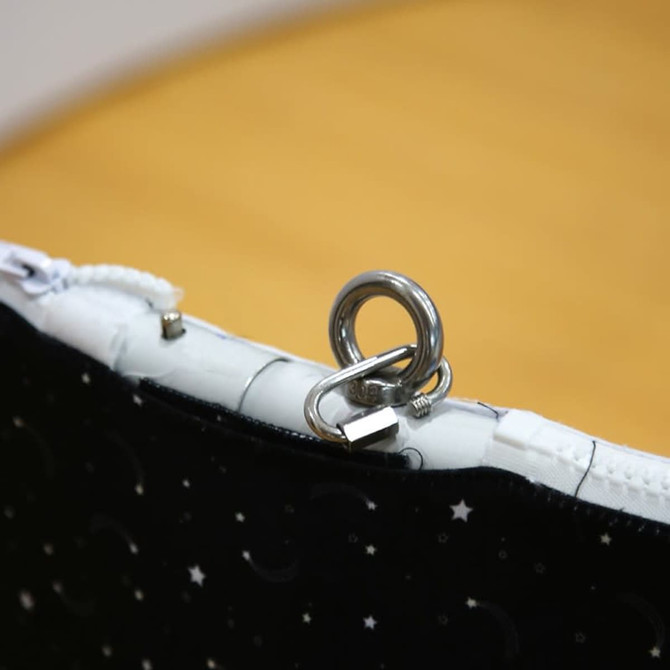 A black fabric pouch with a silver clip and zipper, featuring a celestial pattern of stars and moons.