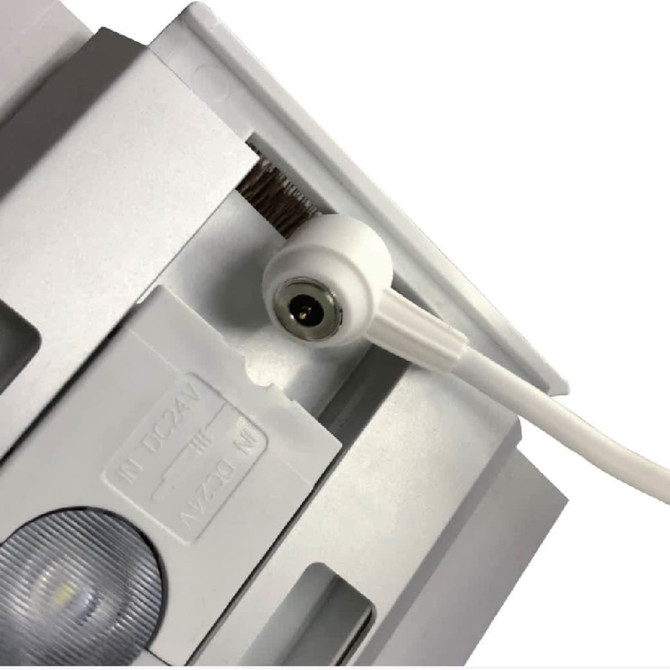 A close-up of a white connector on a light box display, highlighting the electrical input and design details.