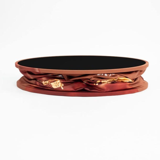 A round display counter with a vibrant brown cover featuring a patterned design. The top has a black surface.