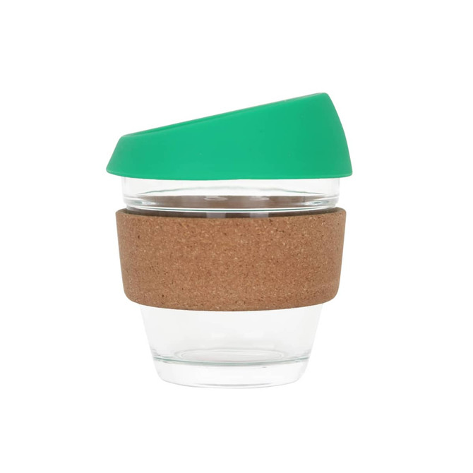 A reusable glass coffee cup with a cork band and a green lid, featuring a clear glass body.
