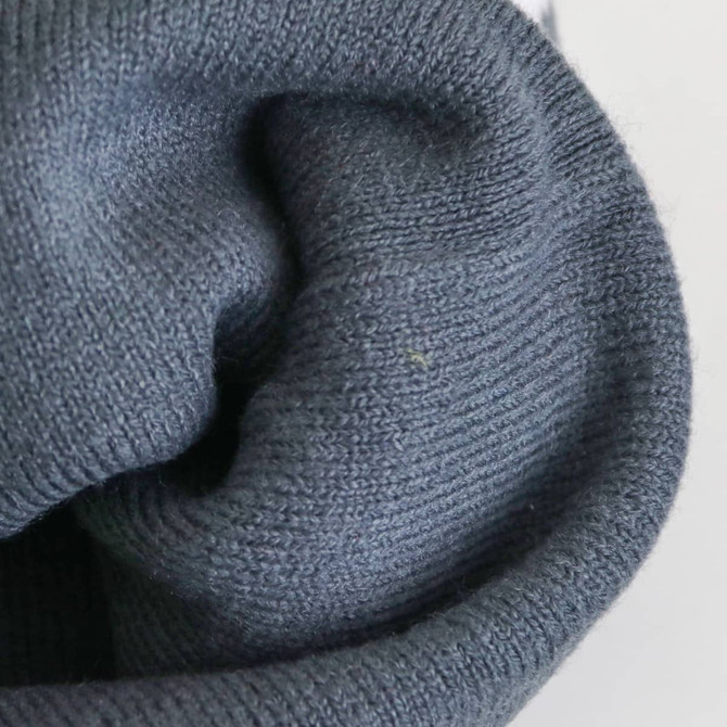 A grey knitted beanie with a soft, textured fabric, featuring a rolled hem and a casual look.