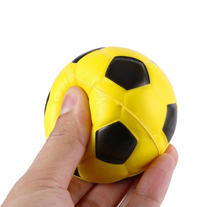 A yellow and black football-shaped stress reliever being squeezed by a hand, featuring a logo.