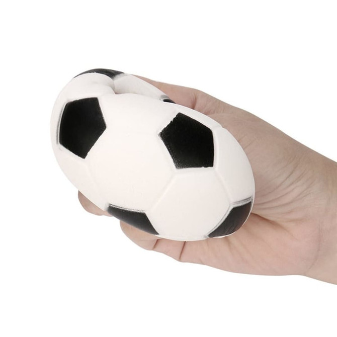 A football-shaped stress reliever in black and white, held in a hand. Features a logo.