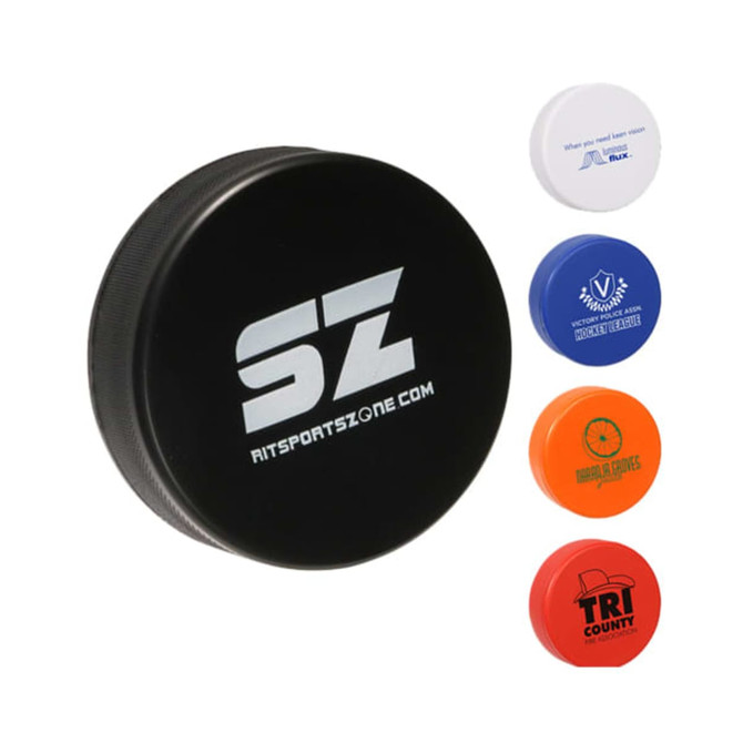 A black hockey puck shape stress reliever with a logo, accompanied by blue, orange, and red stress relievers.