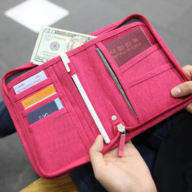 A pink passport holder opens to reveal compartments for cash, cards, and a pen, featuring a logo.