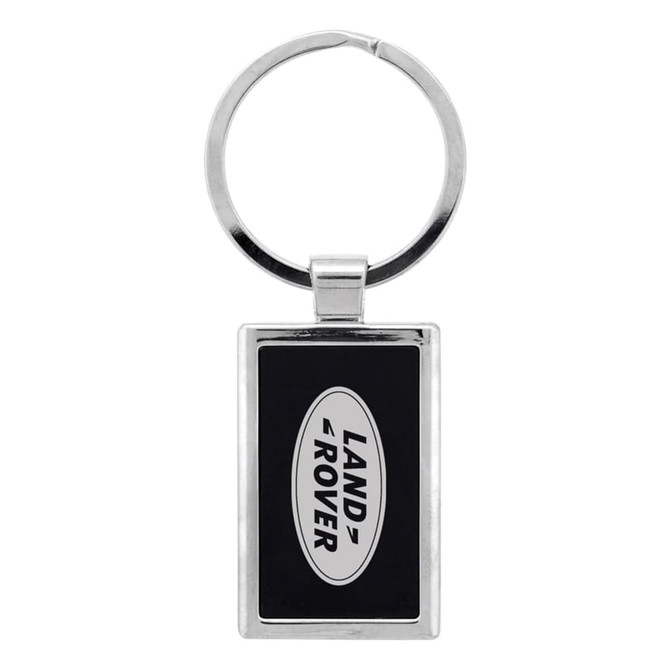 A silver keychain with a rectangular design featuring a black background and a logo.