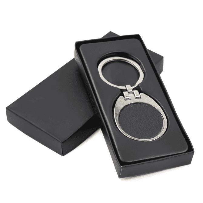 A black leather keychain with a silver metal frame, presented in a sleek black box.
