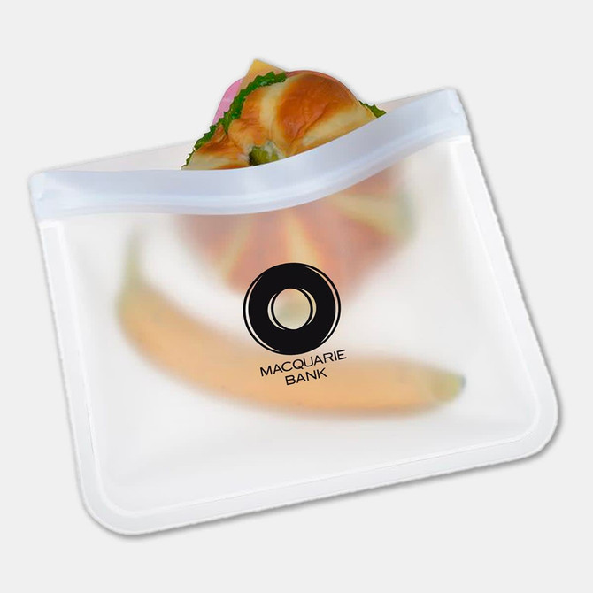 A clear PEVA reusable food storage bag containing a sandwich and a banana, featuring a logo.