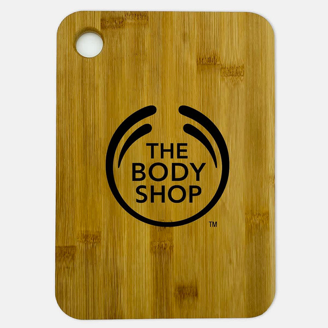 A large bamboo cutting board featuring a round hole and a logo in black.