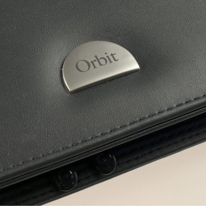 A close-up of a dark grey leather item featuring a metallic silver logo plate.