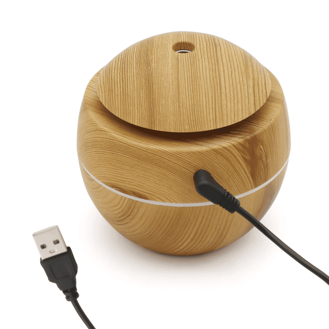 A round, wooden diffuser with a smooth, natural finish and a USB cable. It features a lid on top.