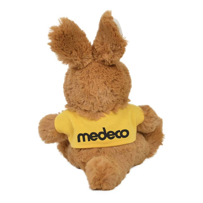 A plush kangaroo toy in tan colour, wearing a yellow shirt with a logo on the back.