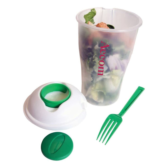 A clear salad shaker with a white lid and green fork, filled with a salad mix. Features a logo on the side.