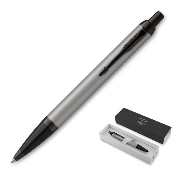 A ballpoint pen in achromatic matte grey, presented in a sleek black box with a brand logo.