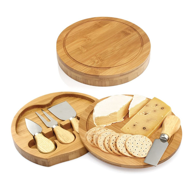 A bamboo cheese set with a circular board, three cheese knives, and slices of cheese and crackers.