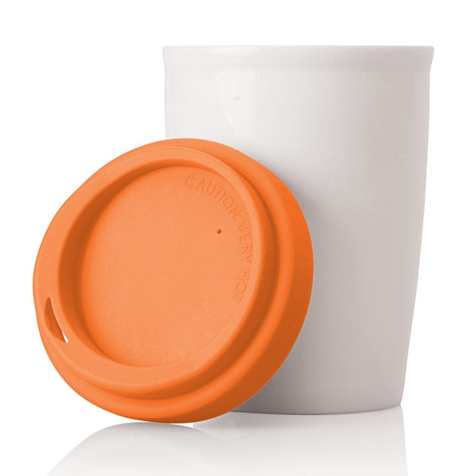 A ceramic white travel mug with an orange silicone lid. Features a logo on the lid.