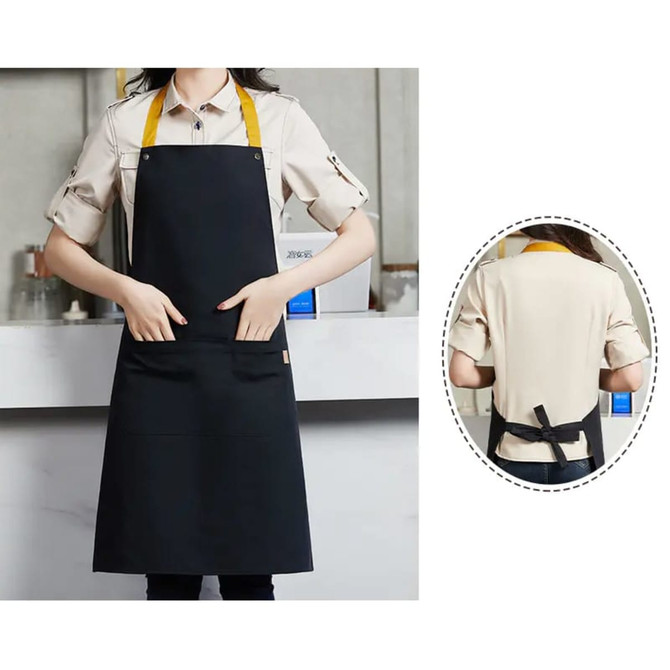 A poly-cotton canvas black bib apron with a yellow neck strap and front pockets. Includes a logo on the fabric.