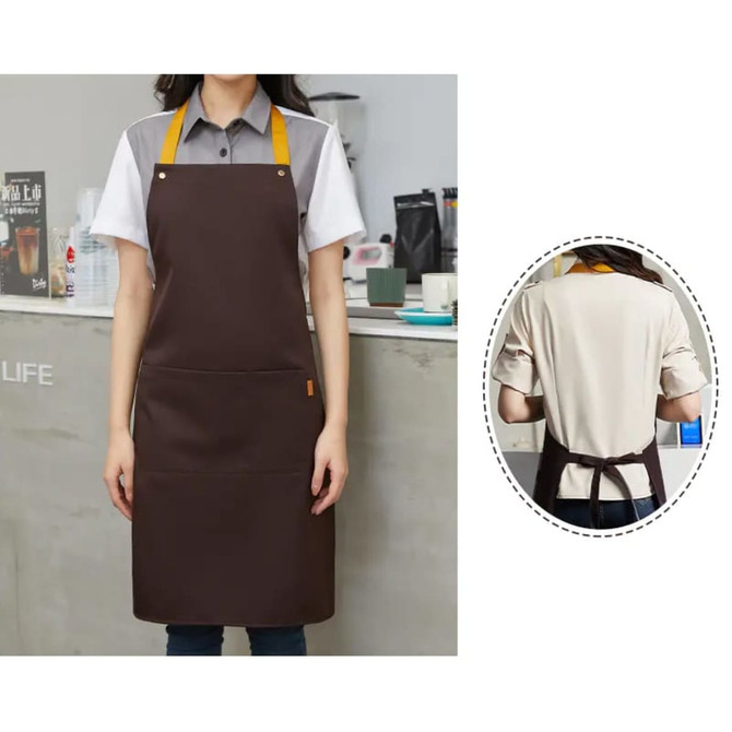A brown poly-cotton canvas full bib apron with a vibrant yellow neck strap and a logo, displayed on a model.