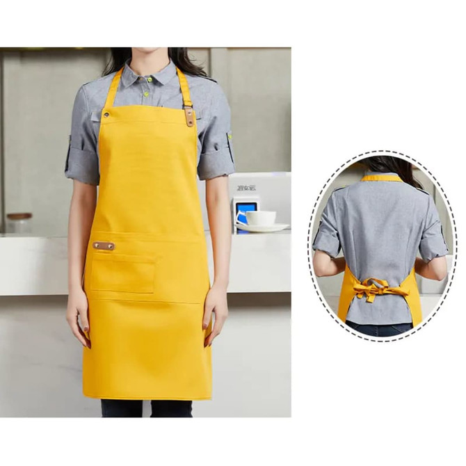 A yellow poly-cotton canvas full bib apron features a neck strap and a front pocket, with a logo.