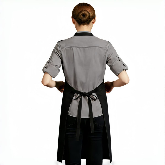 A person wearing a grey shirt and a black poly-cotton canvas full bib apron with neck strap, tied at the back.