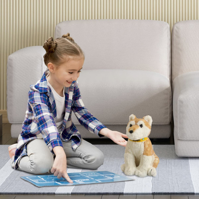 A girl interacts with a tan and cream Dingo plush toy on a rug in a cozy living room setting.