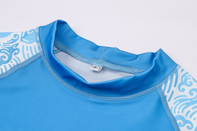 A blue rashie with short sleeves featuring a patterned design on the shoulders. It has a collar and a label inside.