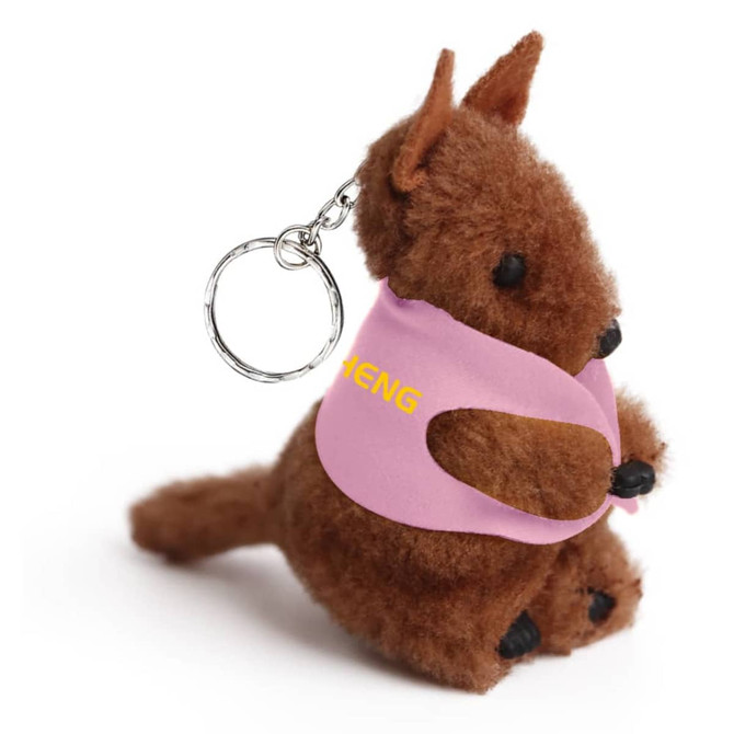 A brown kangaroo plush toy wearing a pink vest, attached to a keyring. It features a small logo on the vest.