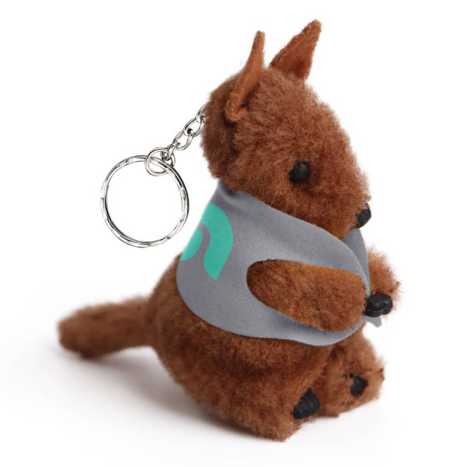 A brown plush kangaroo toy with a keychain, wearing a grey pouch. It has a small tail and black feet.
