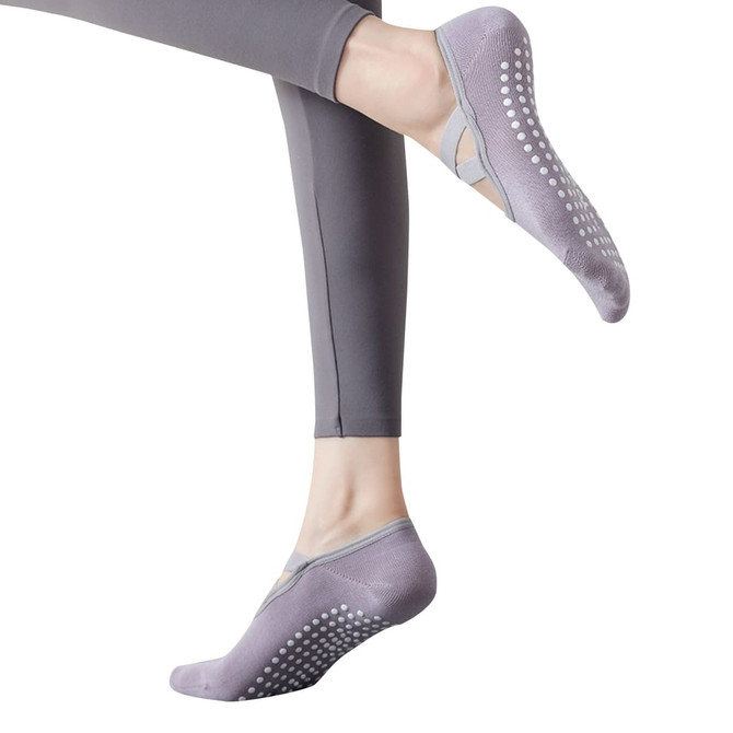 A pair of grey yoga socks with grip dots, worn on a foot, displayed alongside grey leggings.