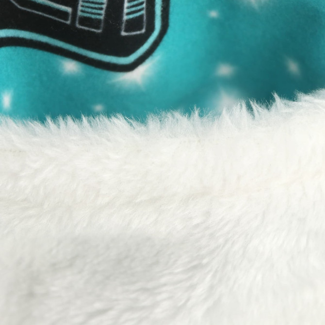 A close-up of a soft, white faux fur trim on a vibrant blue fabric, featuring a pattern.