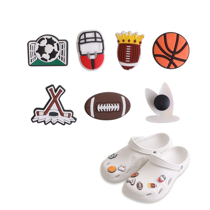 A pair of white Clog shoes with assorted sports-themed charms in green, red, brown, orange and black.