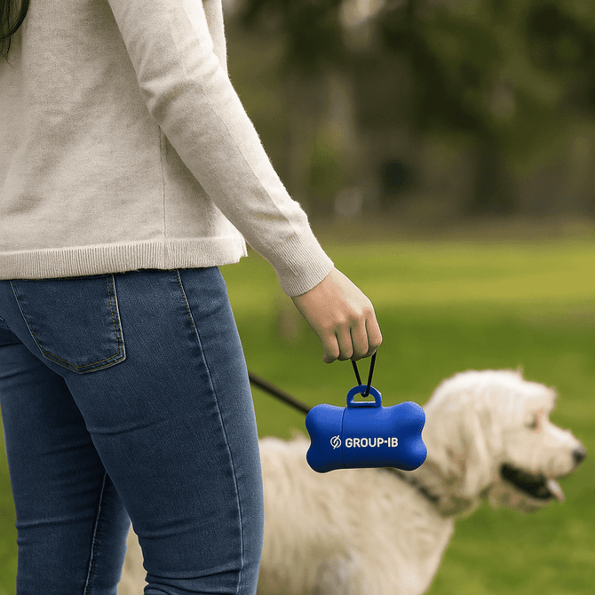 A blue dog waste bag dispenser shaped like a bone is held by a person walking a dog in a grassy park. A blue dog waste bag dispenser shaped like a bone is held by a person walking a dog in a grassy park.